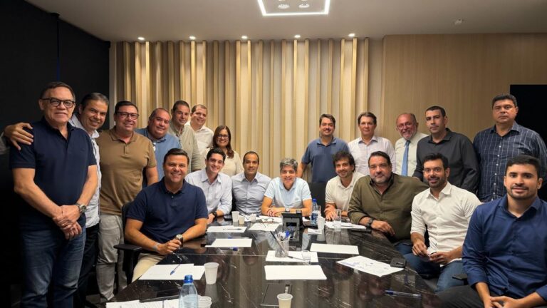 ACM Neto sentado à mesa durante reunião com deputados e lideranças políticas, todos reunidos em um ambiente interno para discutir estratégias eleitorais.