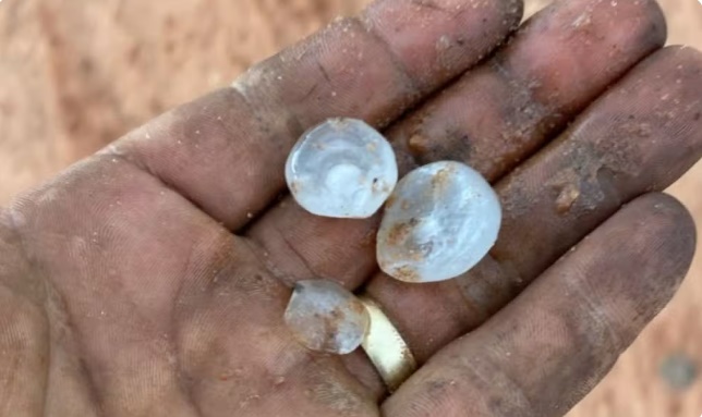 Pedras de granizo cobrindo estrada na zona rural de Luís Eduardo Magalhães após forte chuva.