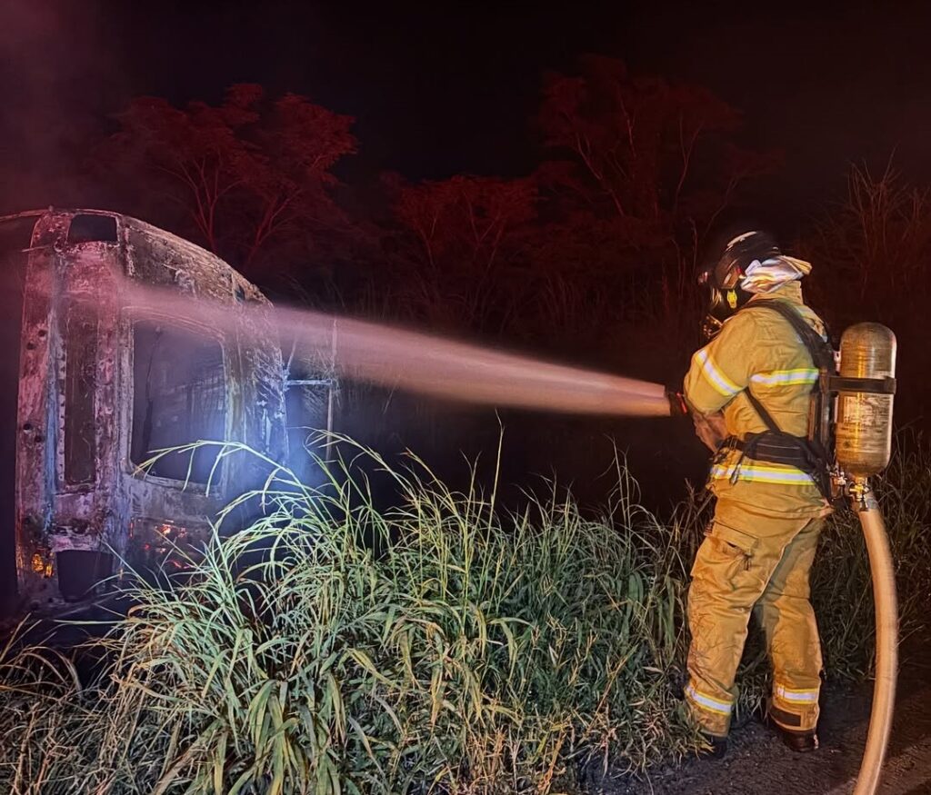 Cabine de caminhão boiadeiro destruída por incêndio na BR-349 enquanto bombeiros realizam rescaldo e controle da área