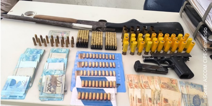 Policiais da CIPE-Semiárido exibem armas, munições e dinheiro apreendidos durante prisão de foragido por homicídio em Buritirama, no oeste da Bahia.