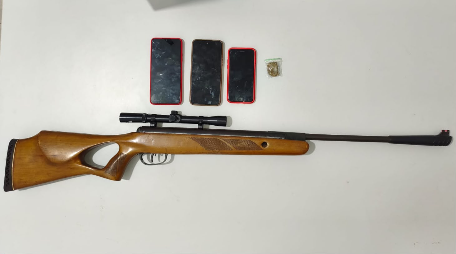 Policiais da CIPE Cerrado durante a prisão de um foragido por homicídio na Rodoviária de Barreiras, com materiais apreendidos, incluindo uma espingarda de pressão, celulares, droga e um sagui.